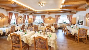 Un comedor con mesas y sillas de madera, manteles blancos y un interior cálido y de madera.