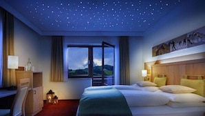 Habitación de hotel con cama, escritorio y ventana con vistas a montañas.