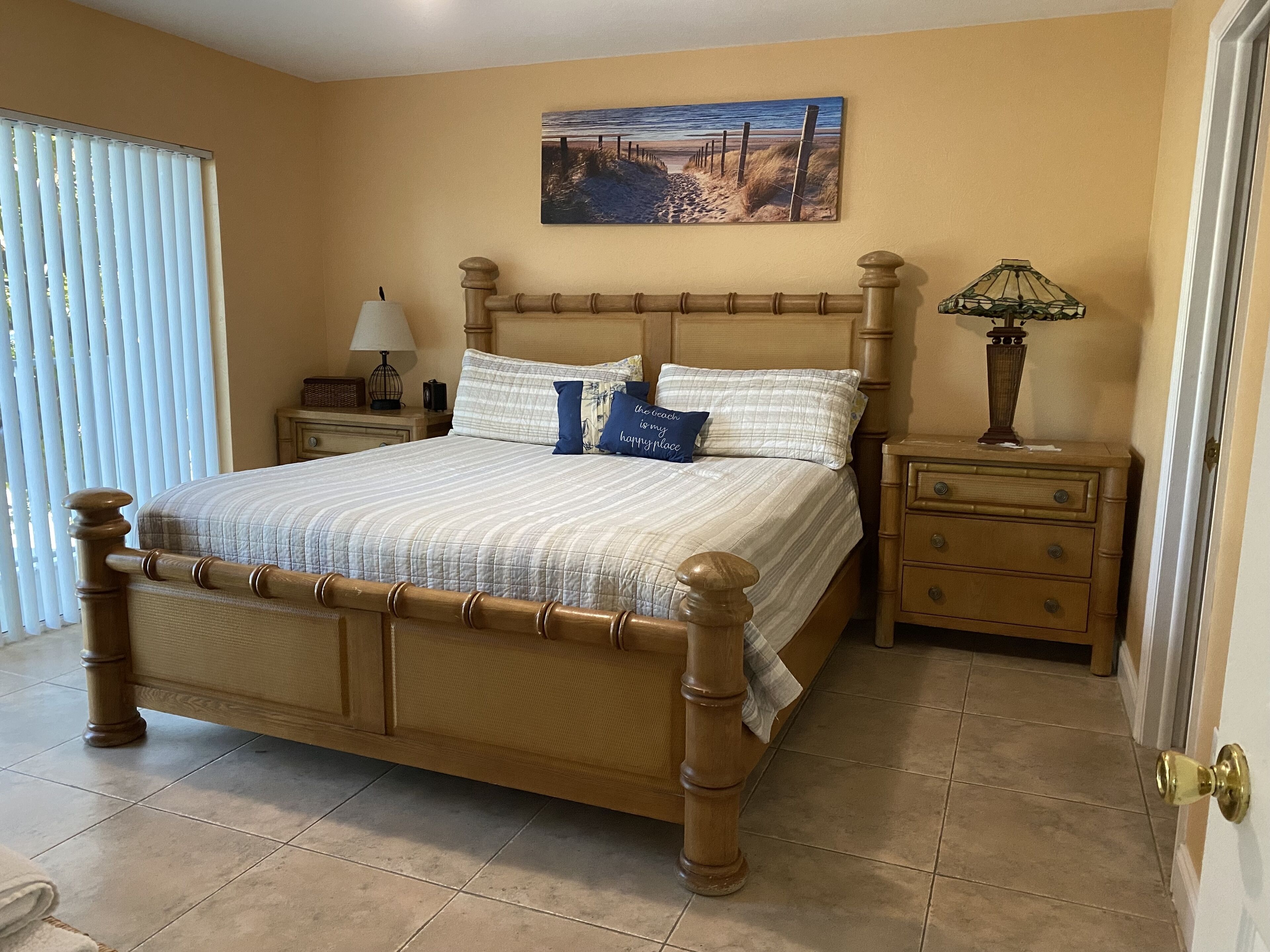 A bedroom with a wooden bed, a nightstand, a lamp, and a painting on the wall.