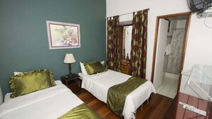 Habitación de hotel con dos camas, una mesita de noche, una lámpara, un cuadro en la pared y zona de ducha.