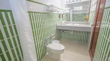 Un baño con azulejos verde a rayas, un inodoro blanco, un lavabo y un espejo.