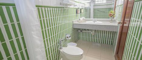 Un baño con azulejos verde a rayas, un inodoro blanco, un lavabo y un espejo.
