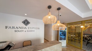 Un área de recepción con mostrador de mármol, un cartel de Faranda Express Soho & Casino y una partición decorativa amarilla.