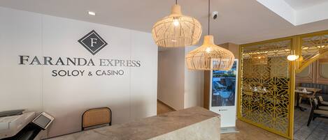 Vastaanottoalue, jossa on marmorinen palvelutiski, Faranda Express Soho & Casino -kyltti ja koristeellinen keltainen sermi.