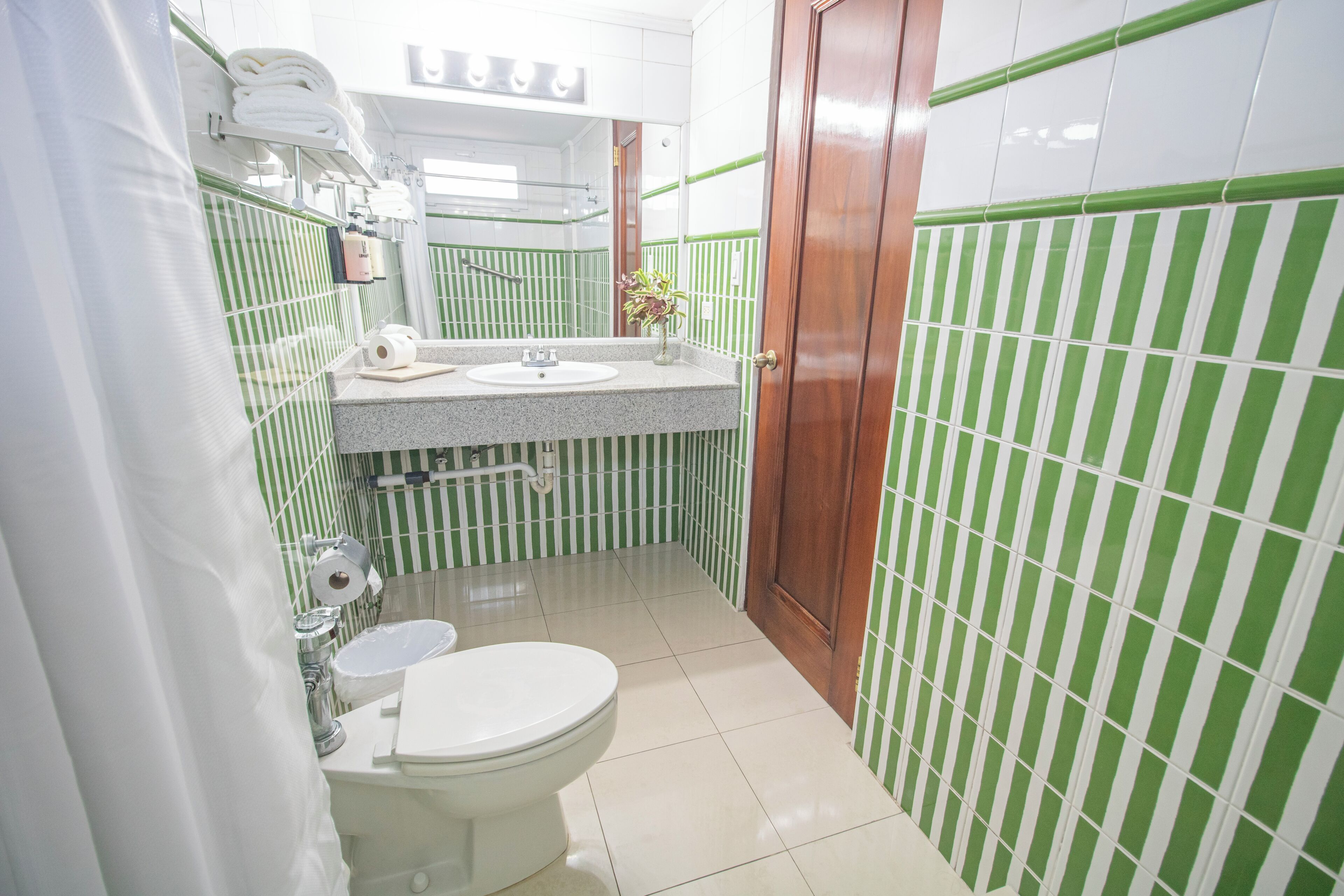 A bathroom with a toilet, sink, and green-striped walls.