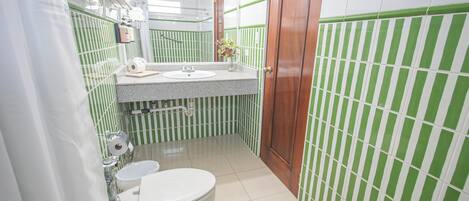 A bathroom with a toilet, sink, and green-striped walls.