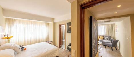 Ein Hotelzimmer mit einem großen Bett, einem Schreibtisch und einer Sitzecke mit einer Couch und Sesseln.