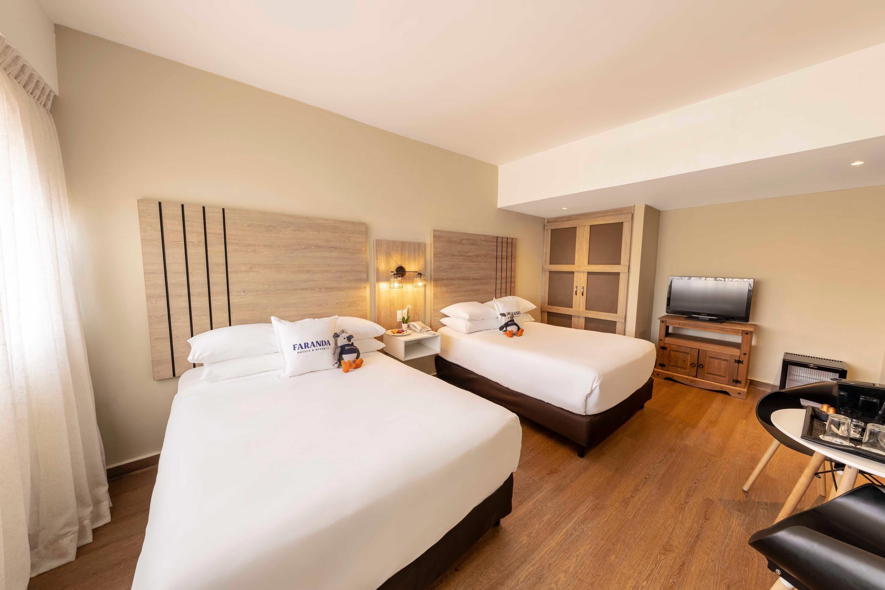 A hotel room with two beds, a TV, a desk, and a wardrobe.