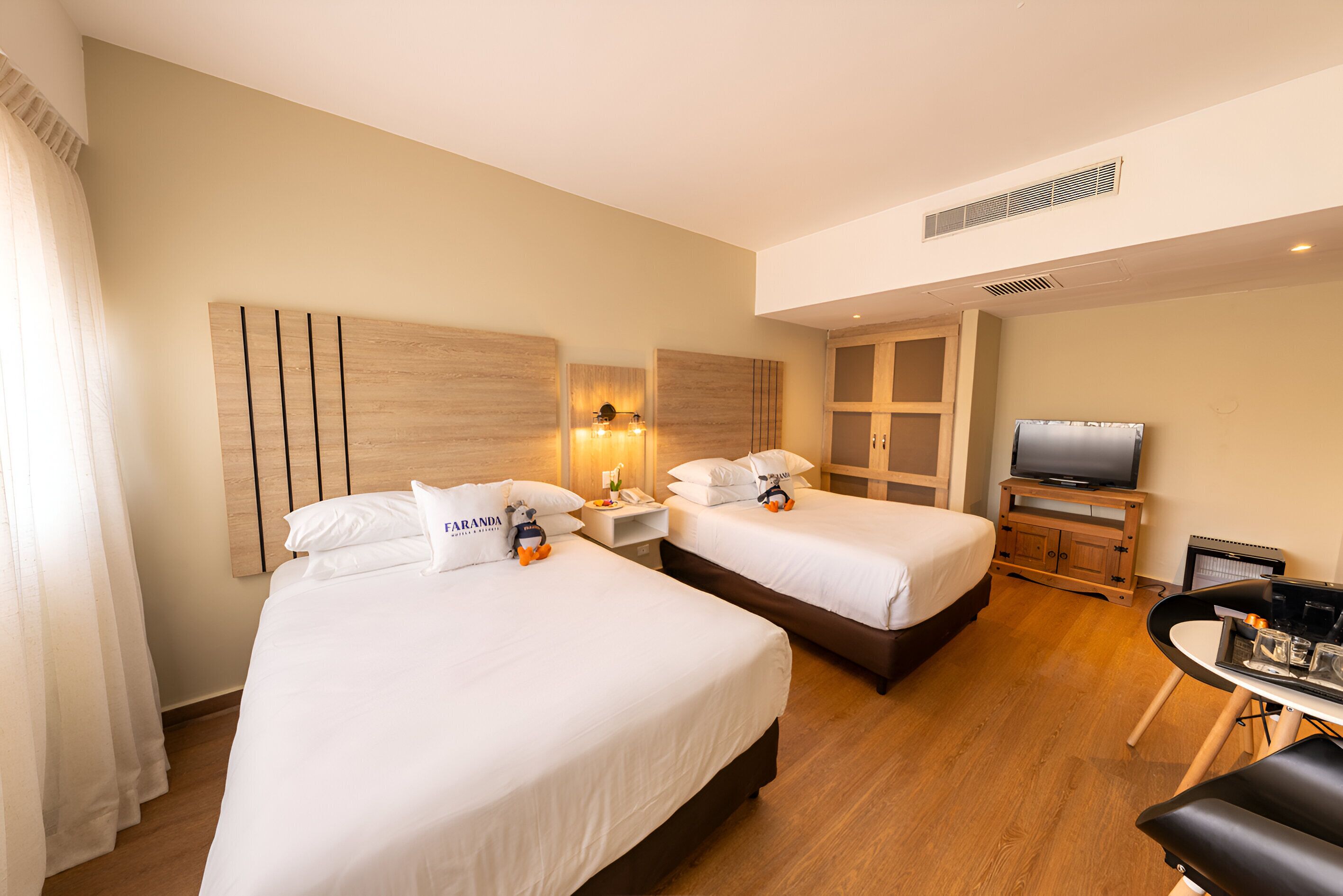 A hotel room with two beds, a TV, a desk, and a chair.