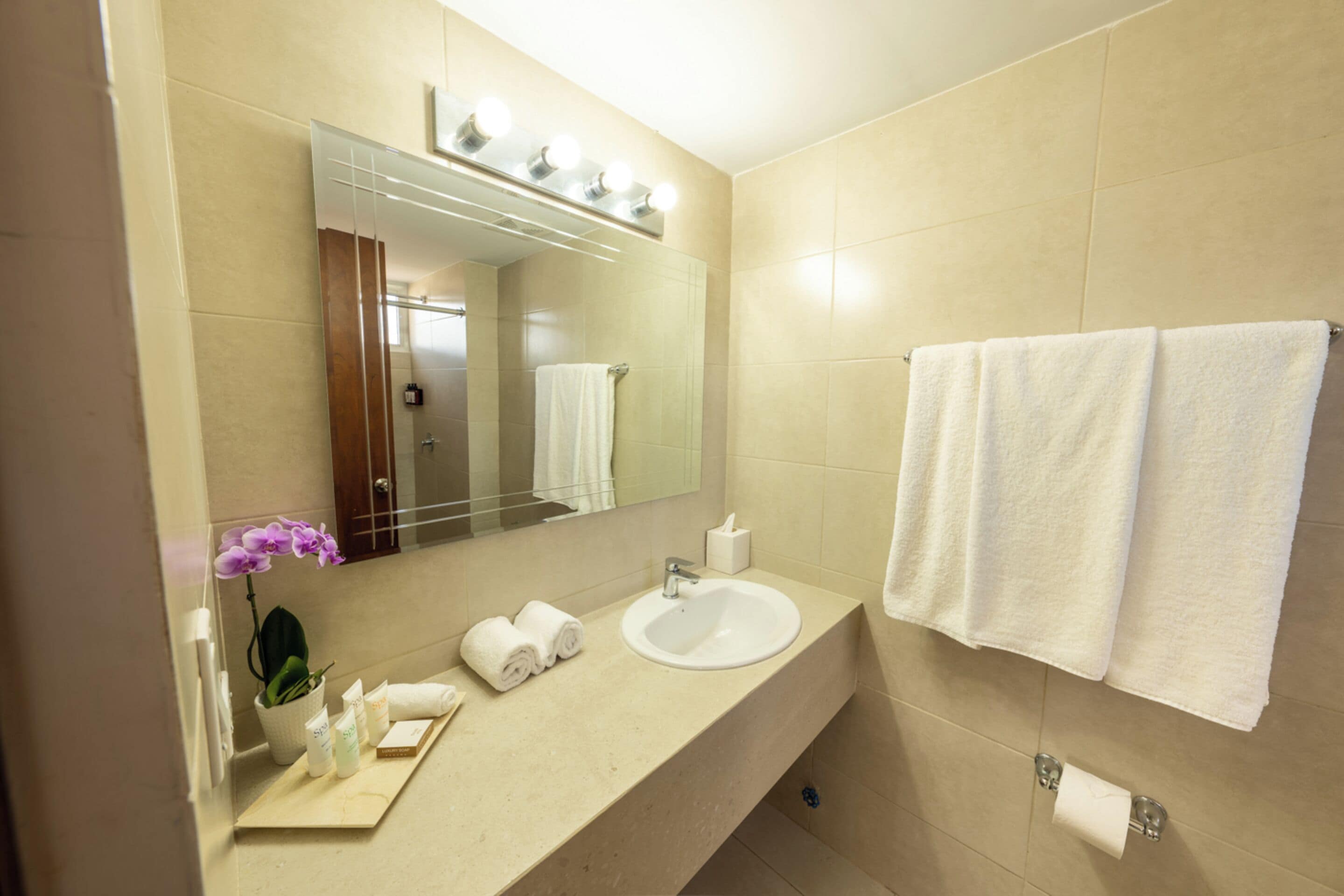 A bathroom with a sink, mirror, and two towels hanging on the wall.