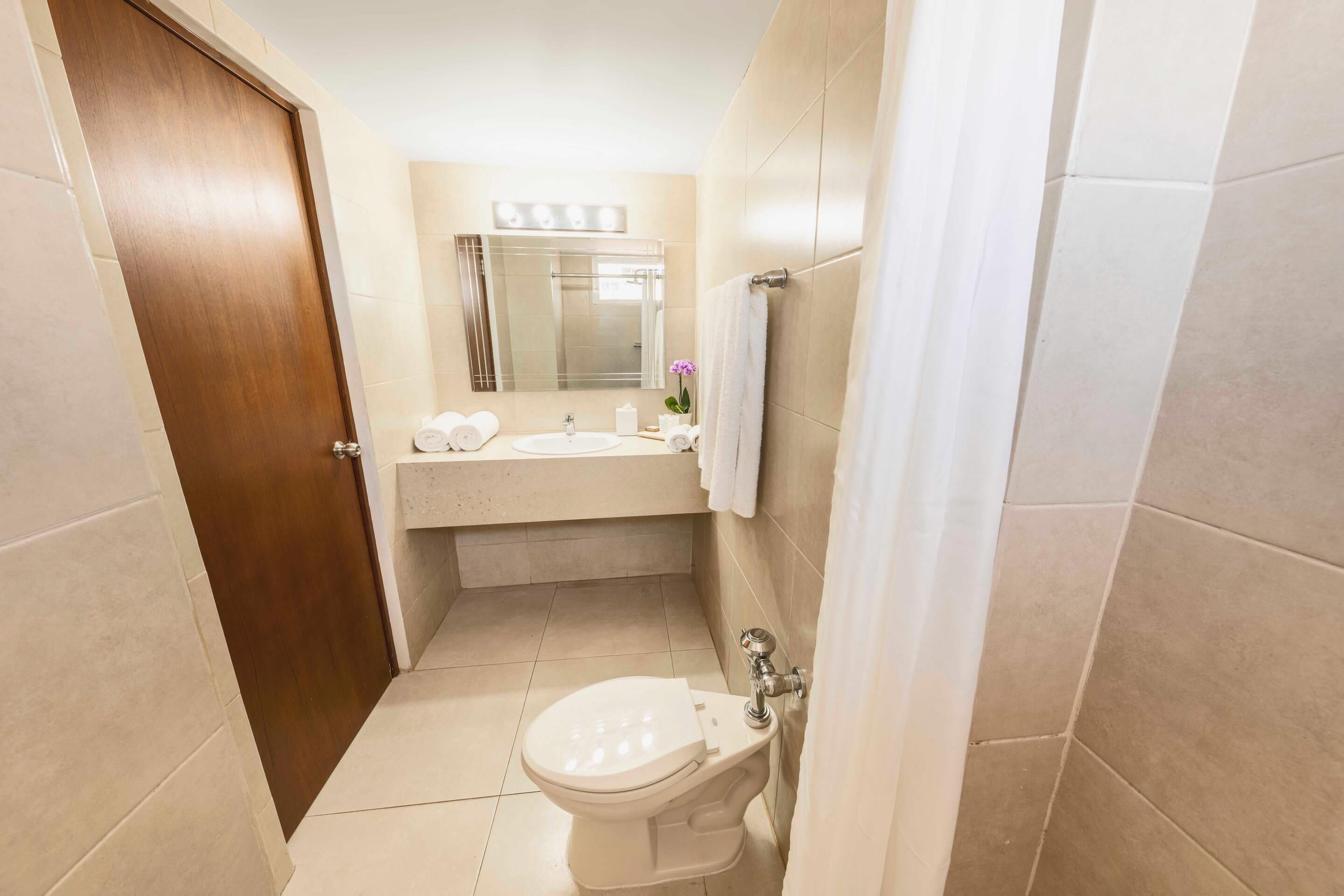 A compact bathroom with a toilet, sink, and mirror.