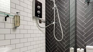 A modern bathroom with white subway tiles, a black herringbone-patterned shower wall, a glass-enclosed shower, a white sink, and a toilet. - Sea view, pet friendly central Laines location, 1 minute from station  (Brighton)