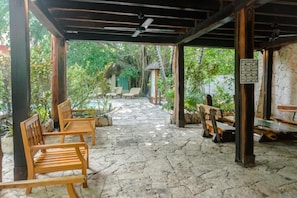 Relax in a serene outdoor space surrounded by lush greenery and a thatched-roof structure.