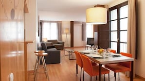 A modern hotel room with a dining area, a sofa, and a TV. - MH Apartments Opera Rambla (Barcelona)