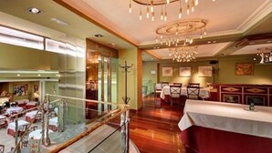 A restaurant with multiple dining areas, a glass railing, and a chandelier. - Hispanos Siete Suiza (Barcelona)