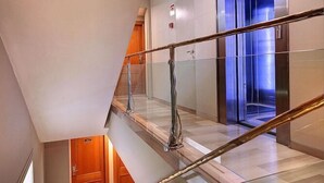A modern interior with a glass staircase, a wooden door, and an elevator. - Hispanos Siete Suiza (Barcelona)