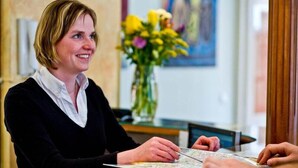 A person seated at a table with a map, in a room with a vase of flowers and a painting on the wall. - Melantrich Sivek Hotels (Prague)
