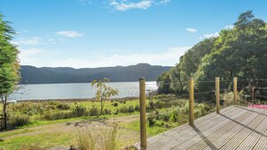 A wooden deck overlooking a lake with mountains in the background.