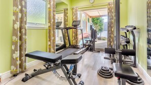 A gym with exercise equipment, a treadmill, and a bench.