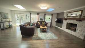 A spacious living room with a fireplace, a sofa, a coffee table, and a television.