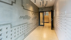 A modern hallway with a concrete wall design, a series of lockers on the right, and a door leading to another area.
