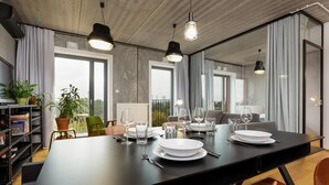 A modern dining area with a large table set for four, large windows, and a city view.