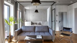 A modern living room with a grey sofa, a black chair, a coffee table, and a large window with curtains.
