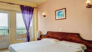 A hotel room with a large bed, a window with curtains, a wall-mounted light, and a framed picture. - Estrella Hotel (Manacor)