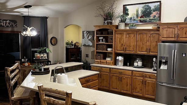A modern kitchen with wooden cabinets, a central island, and bar stools. - Mountain View Spacious Ranch Home AMAZING VIEW (Milliken)