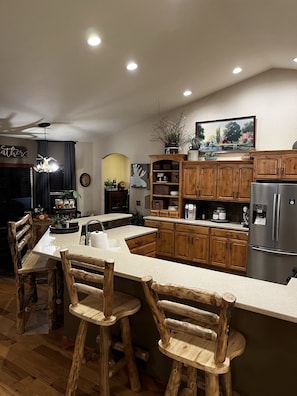 A modern kitchen with wooden cabinets, a central island, and bar stools.
