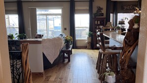A spacious living area with a wooden floor, a dining table, and a kitchen area with a wooden chair. - Mountain View Spacious Ranch Home AMAZING VIEW (Milliken)