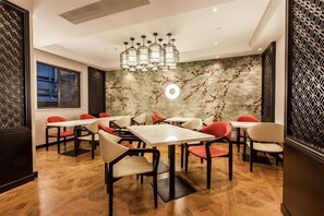 Un espace repas moderne avec une table centrale entourée de chaises, un mur décoratif orné d’un motif circulaire et un paravent à motifs sur le côté gauche.