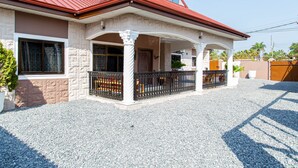 Ein Haus mit rotem Dach, Steinaußenwand und einem Schotterweg.