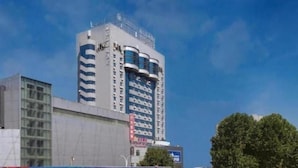 A multi-story building with a modern architectural design, featuring a prominent glass facade and a series of balconies.