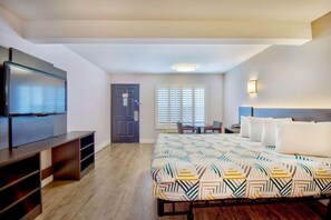 A hotel room with a bed, a TV, a desk, and a chair.