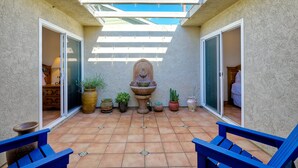 A patio with a blue bench, a decorative fountain, and potted plants. - Hacienda Decor, Fully Fenced Backyard, Spacious (Carlsbad)