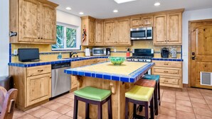 A kitchen with wooden cabinets, a tiled island, and a dishwasher. - Hacienda Decor, Fully Fenced Backyard, Spacious (Carlsbad)