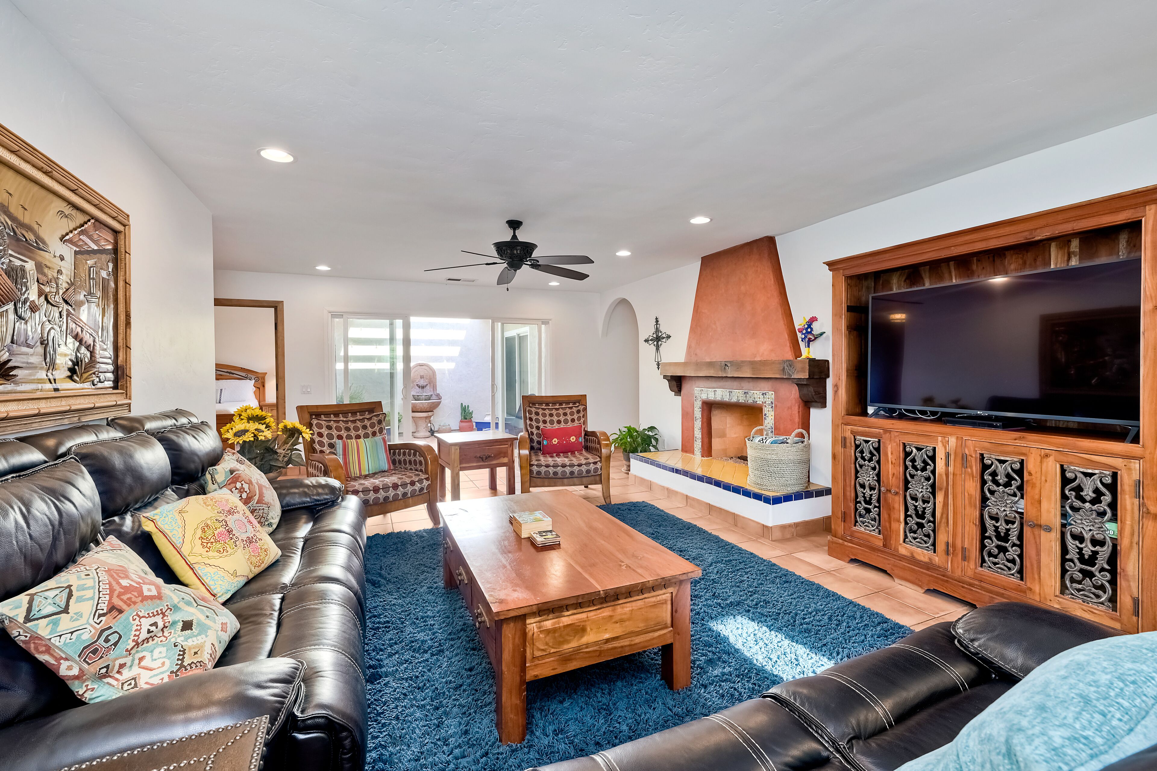 A living room with a leather sofa, a wooden coffee table, a fireplace, and a television.