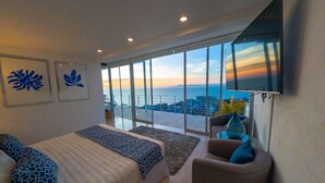 Une chambre moderne avec un grand lit, un coin salon et un téléviseur.