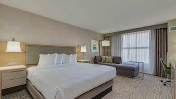 Una habitación de hotel con una cama grande, un sofá, un escritorio y una silla.