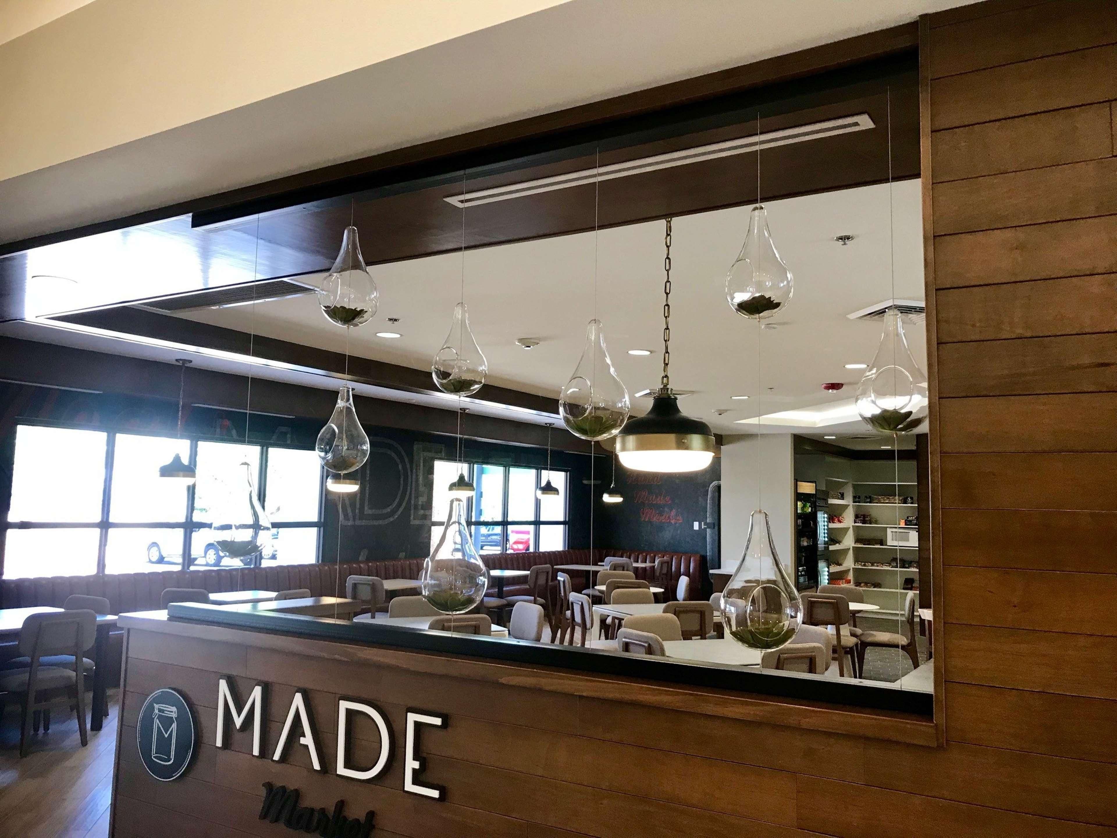 L’intérieur d’un restaurant, avec un comptoir en bois, des suspensions décoratives et une vue sur la salle à manger.