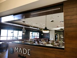 Een restaurantinterieur met een houten toonbank, hangende吊灯 en een uitzicht op de eetzalen.
