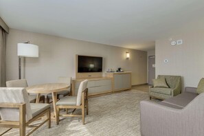 A hotel room with a dining table, chairs, a sofa, a TV, and a minibar. - Doubletree by Hilton Phoenix Chandler (Chandler)