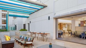 An outdoor patio area with seating, a fire feature, and a covered walkway.