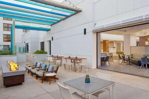 An outdoor patio area with seating, a fire feature, and a covered walkway. - Doubletree by Hilton Phoenix Chandler (Chandler)
