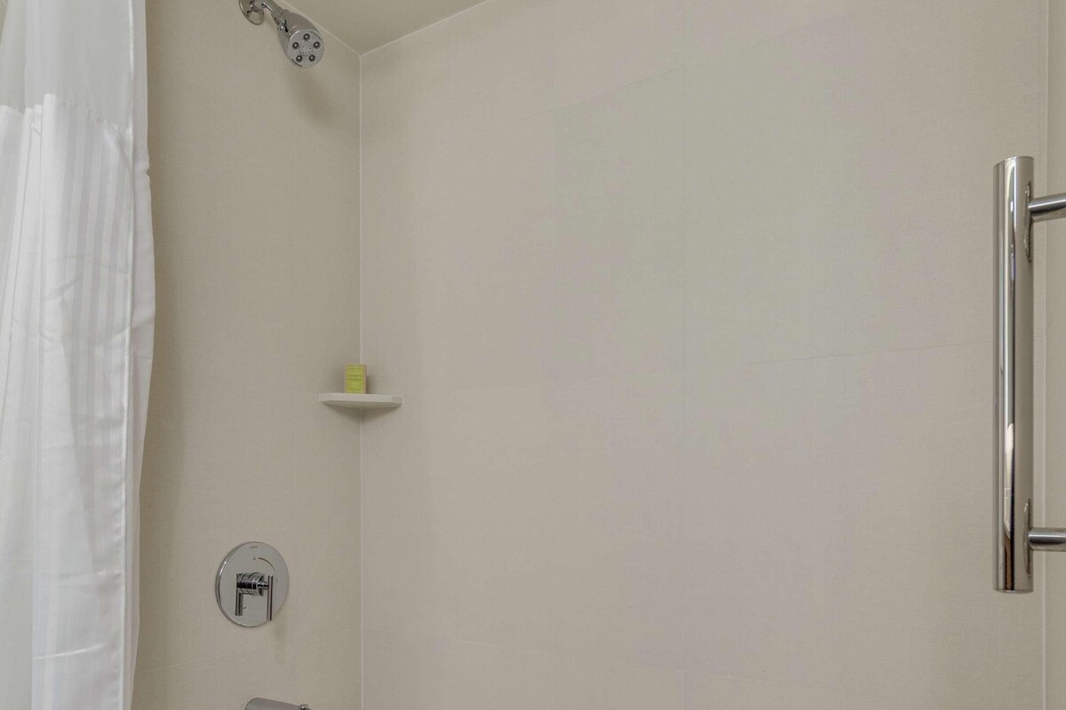 A bathroom with a bathtub, shower, and a towel rack.
