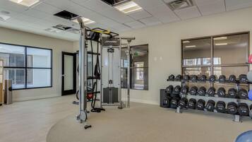 Un gimnasio con equipamiento para levantamiento de pesas, mancuernas y una barra de dominadas.