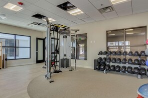 Ein Fitnessstudio mit Krafttrainingsgeräten, Kurzhanteln und einer Klimmzugstange.