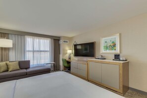 A hotel room with a bed, a sofa, a TV, a desk, and a painting on the wall. - Doubletree by Hilton Phoenix Chandler (Chandler)