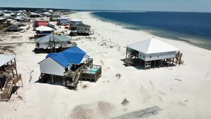 A beachside resort with multiple bungalow-style buildings, some with elevated platforms, and a clear view of the ocean. - Island Time II - 102 Raphael S (Dauphin Island)